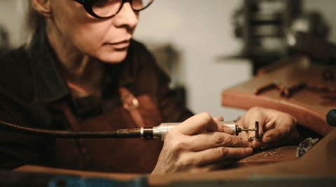 A jewelry artisan polishing a ring at their workbench.