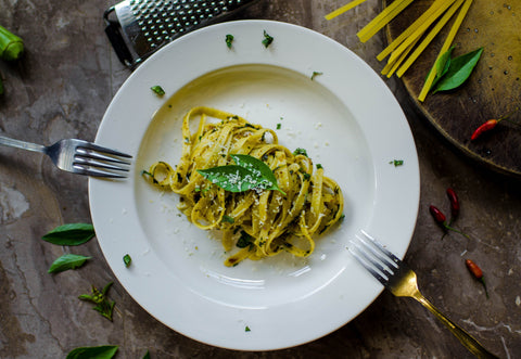 Plate of pasta with basil, parsley and two forks