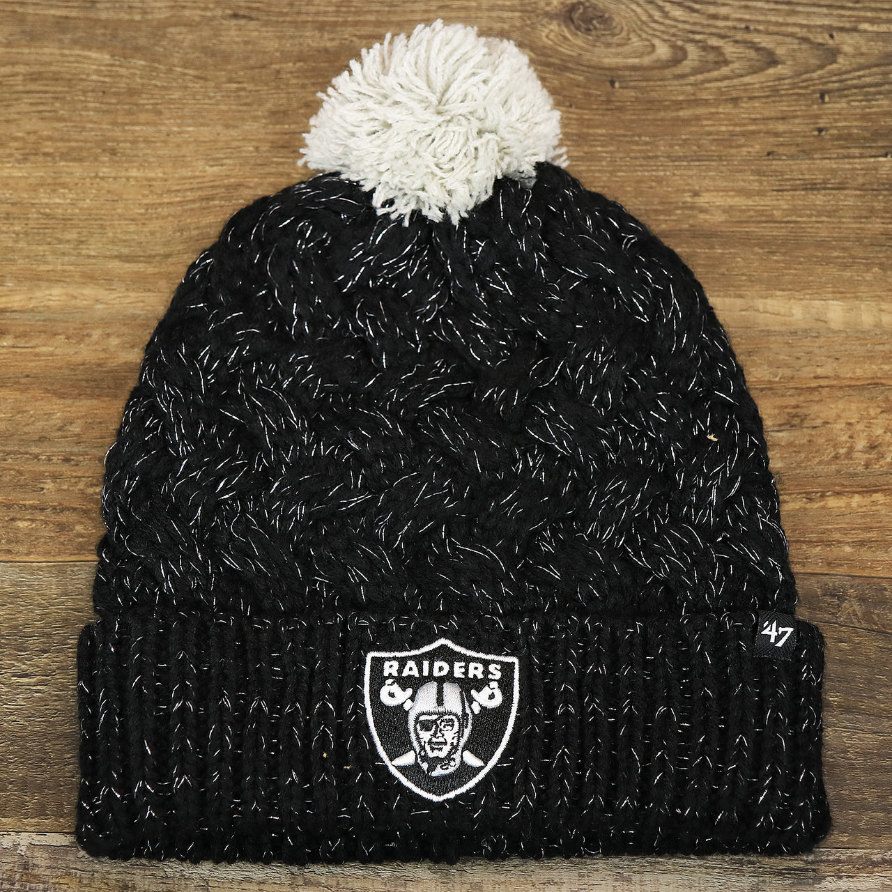 The front of the Women’s Las Vegas Raiders Reflective Silver Cuffed Pom Pom Winter Beanie | Black Winter Beanie