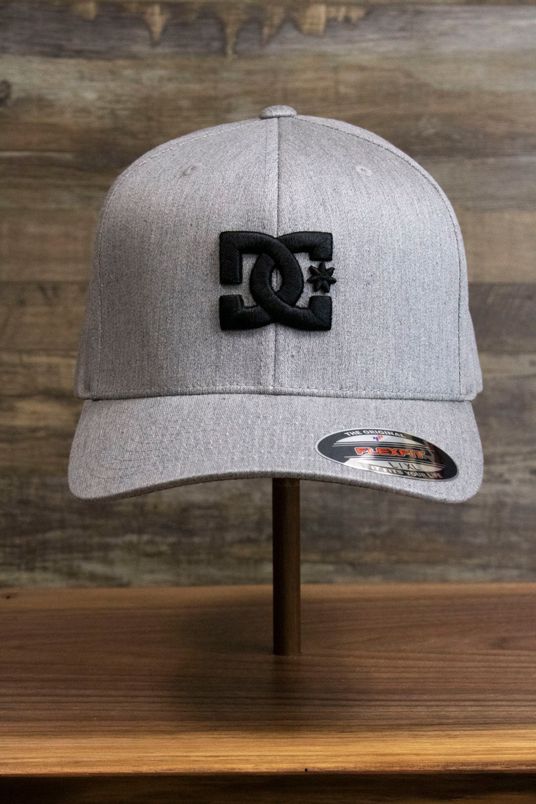 the Light Gray Bentbrim Skater Hat | DC Shoes Black Bottom Heather Gray Flexfit Cap has a black DC logo on the front