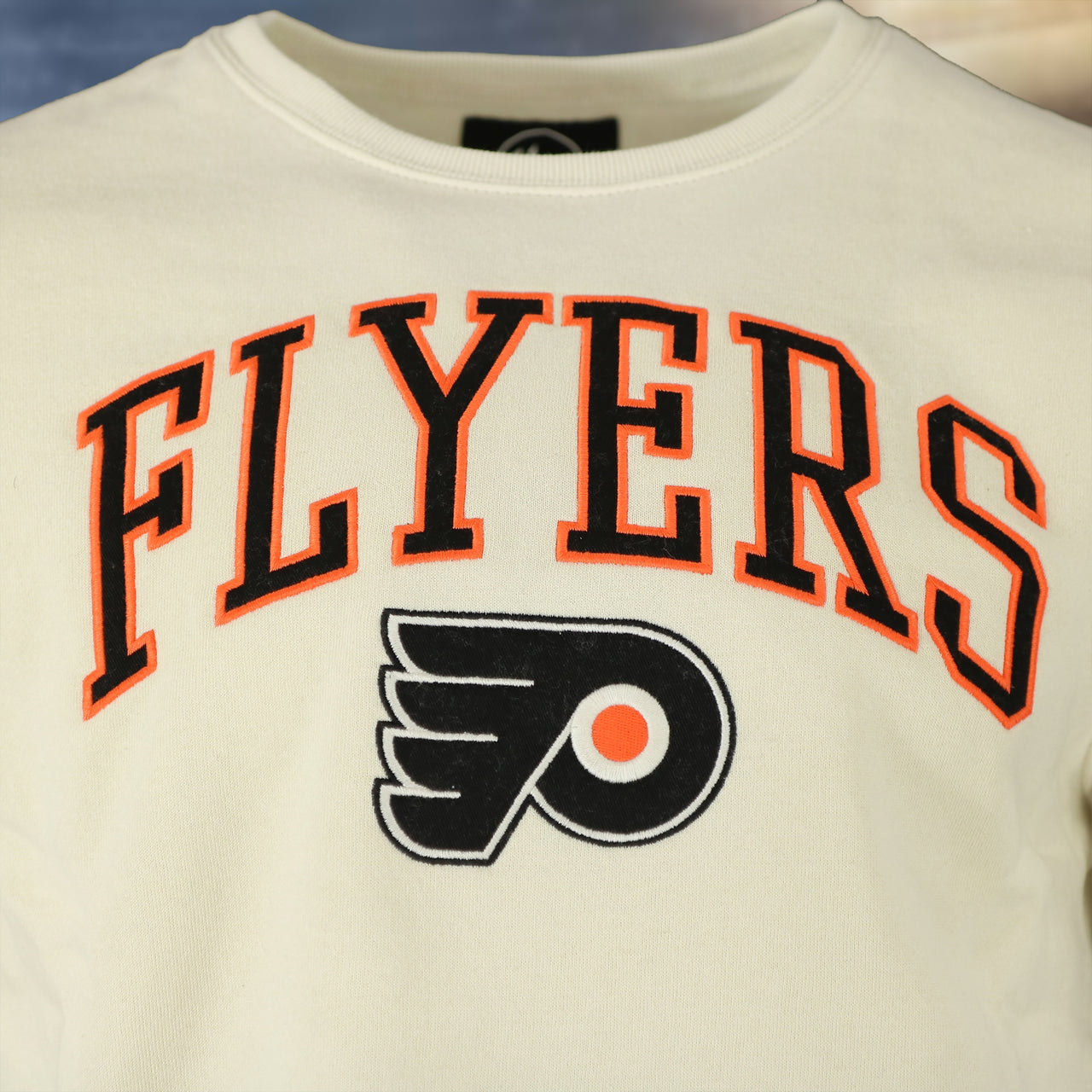 logo on the front of the Philadelphia Flyers Arch Logo Game Break Headline Natural Crewneck Sweatshirt