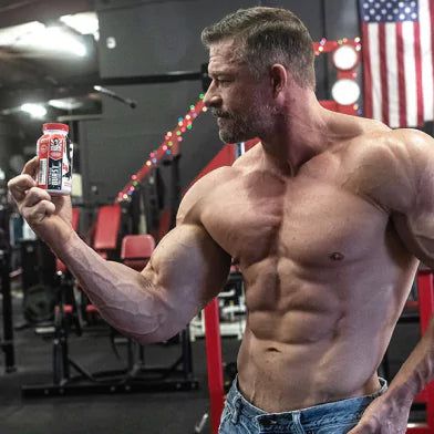 Muscular man in a gym holding a container, examining it.