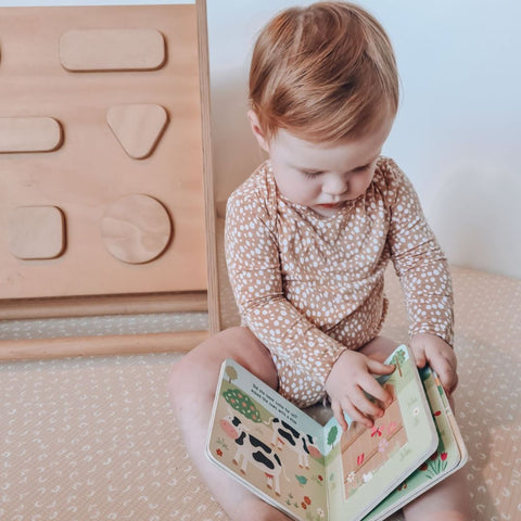 Toddler reading on baby play mat