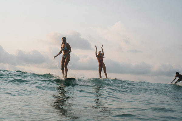 Two girls surfing in scenic setting both smiling and cheering