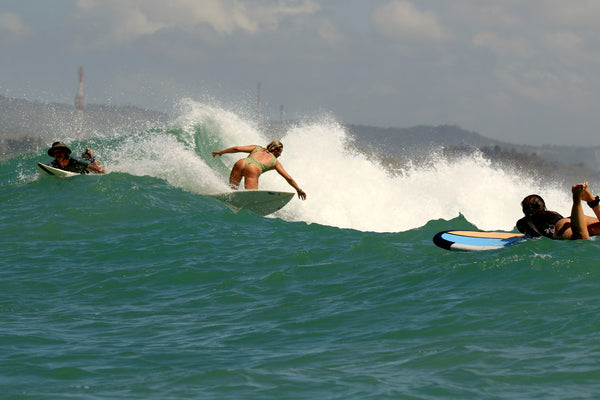 Female surfer surfing a right hander wave, making a turn wearing a spring surfsuit