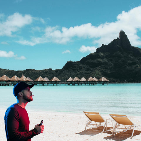 man sitting on a beach with a vape on vacation