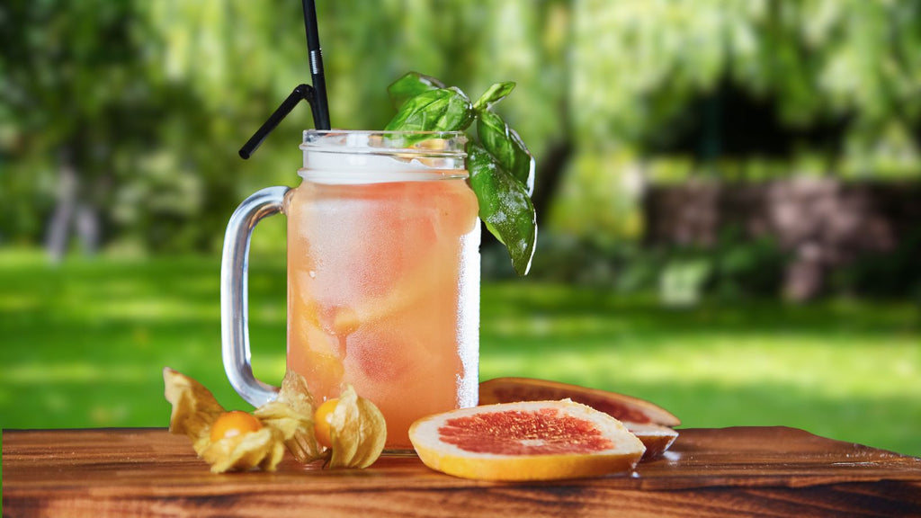 Basil grapefruit gin and tonic in a mason jar mug overlooking a backyard