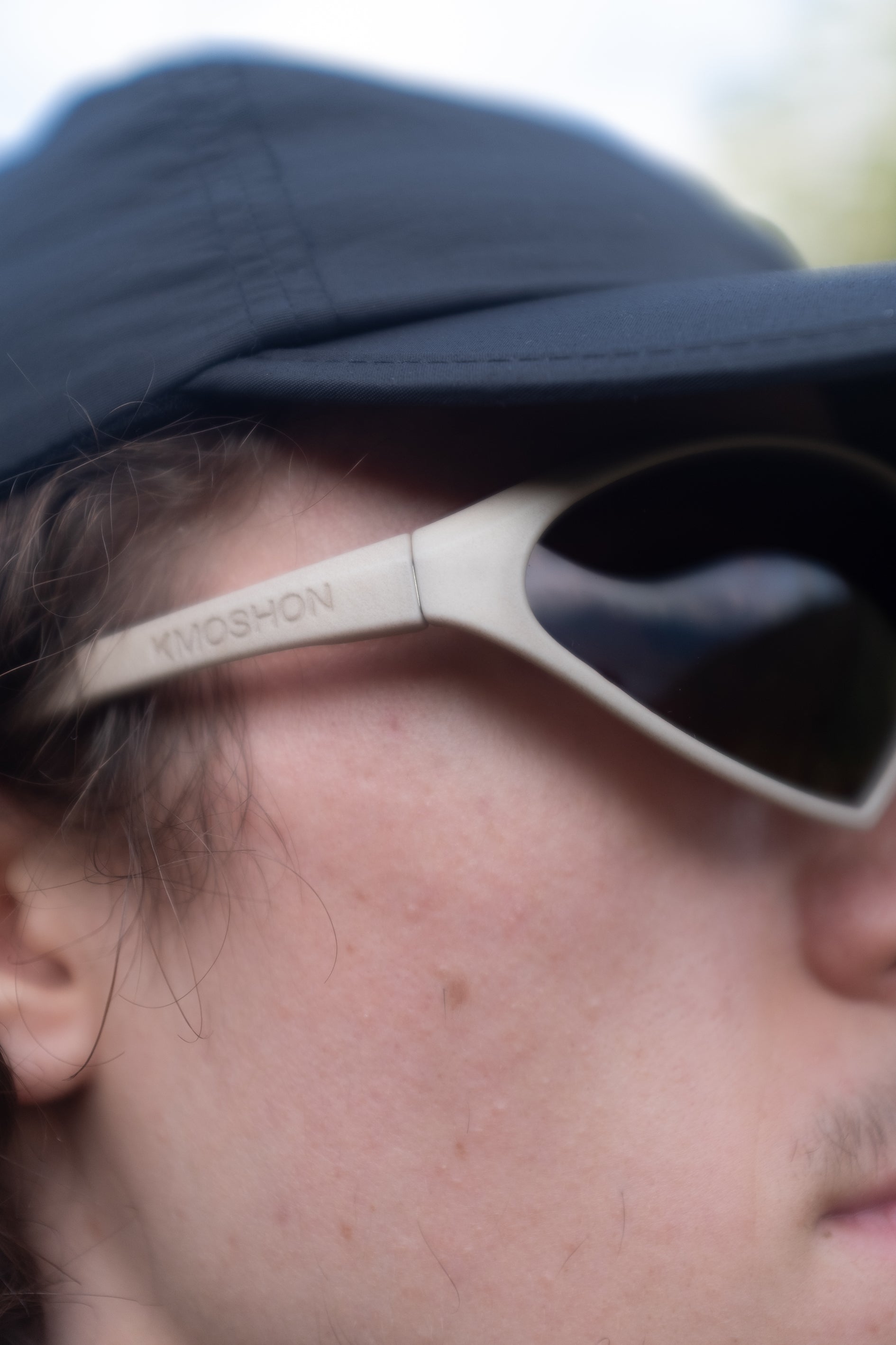 Close up of Kmoshon sunglasses from the side worn by a man in a cap