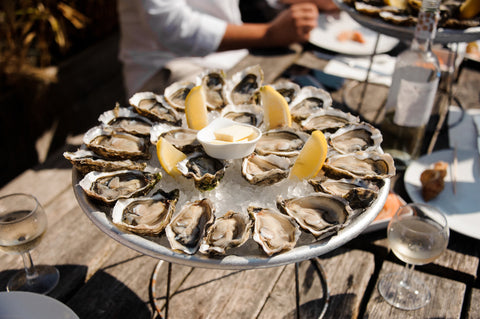 A group of people enjoying oysters and drinks at an oyster bar in Charleston