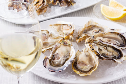 A glass of white wine and a plate of oysters