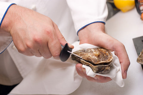 A person shucking oysters at an oyster bar
