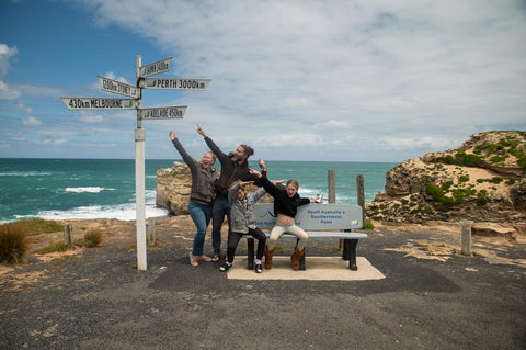 Family (Our Sunkissed Days) at Australia's southern most point pointing at sign with distances to Australian cities