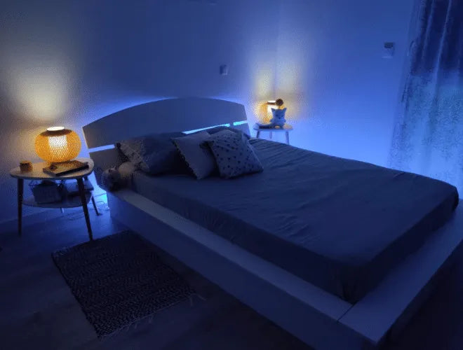 The bed in the bedroom is set up with blue lighting LED strip above the bed.
