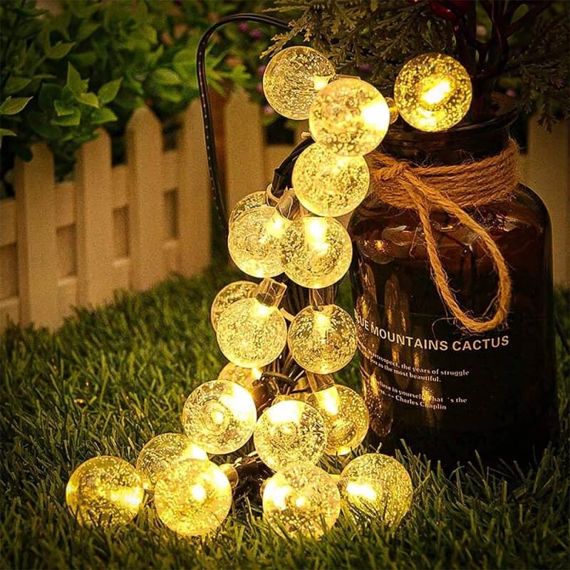 Alphabet vases with Christmas tree branches decorated with solar string lights.