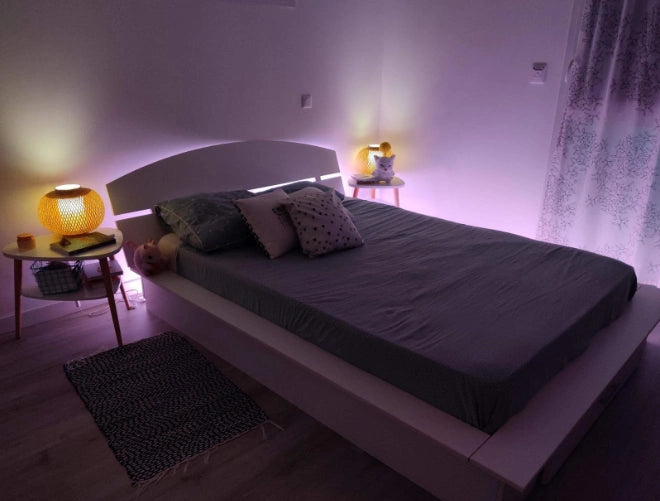 The headboard is fitted with LED strips and set up with pink lighting as a night light.