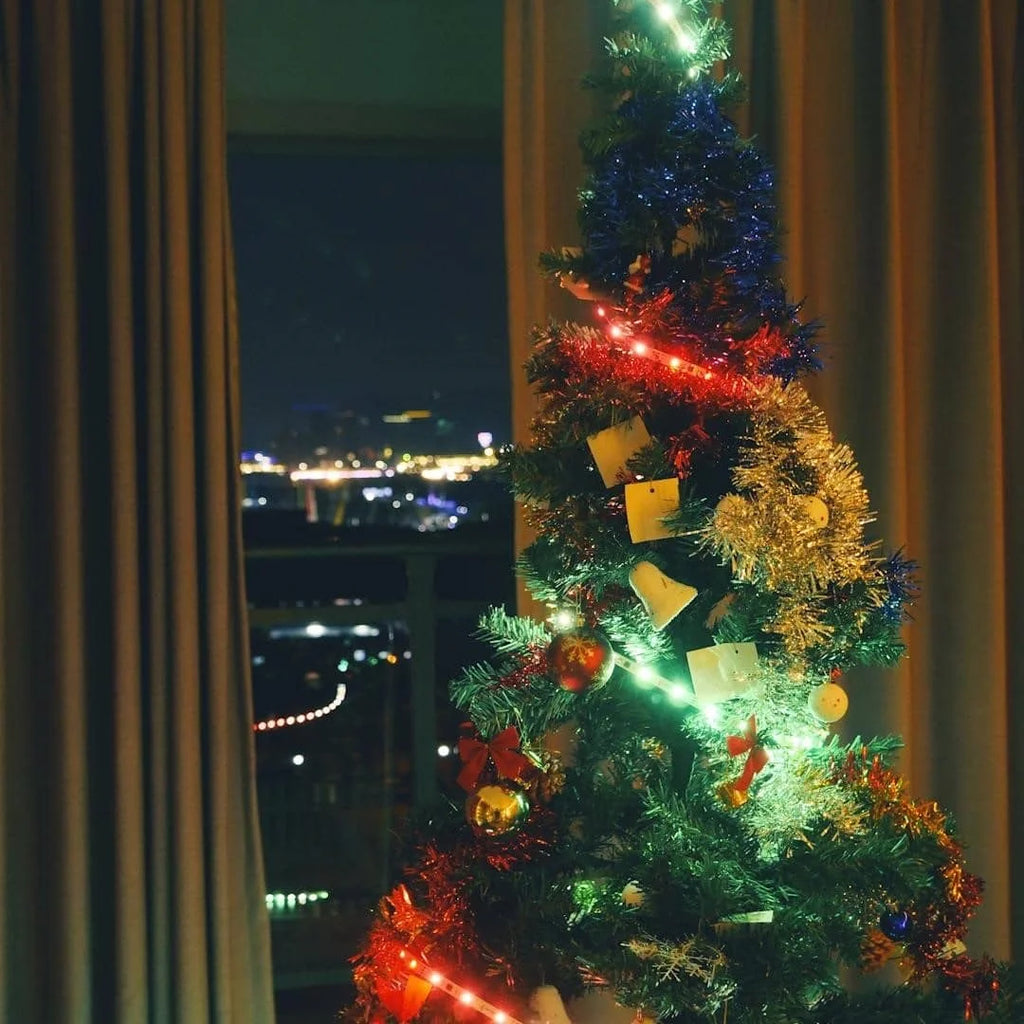 Um den Weihnachtsbaum gewickelte LED-Streifen mit Kugeln, beleuchtet in zwei Farben, rot und grün, für dekorative Beleuchtung.