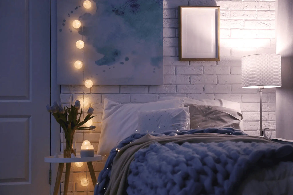 The bed in the bedroom is adorned with warm color string lights beside it for mood lighting.