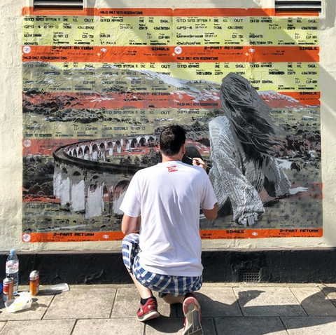 Johnman Spraycan painting a train ticket street art mural at the Cheltenham Paint Festival