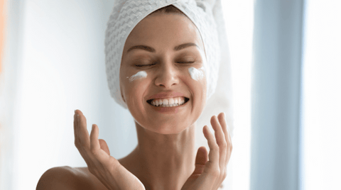 A woman applying a moisturiser on her face.