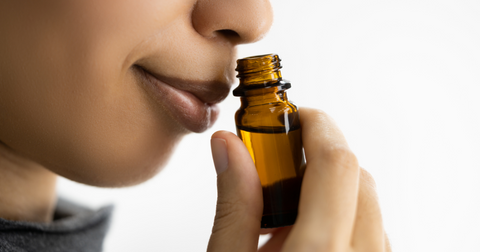 A woman smelling essential oil bottle