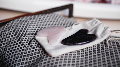 Rose and black obsidian Gua Sha tools on top of a string straw bag | Jenny Nordic Skincare