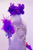 White sequined halter leotard has large crystal sequined appliques along left front bodice. Purple feathers and a hot pink ruffle cover from the left hip around the back.  There is a purple sequined and feather accest in the right shoulder. Comes with purple feather hair accessory. Front Zoom