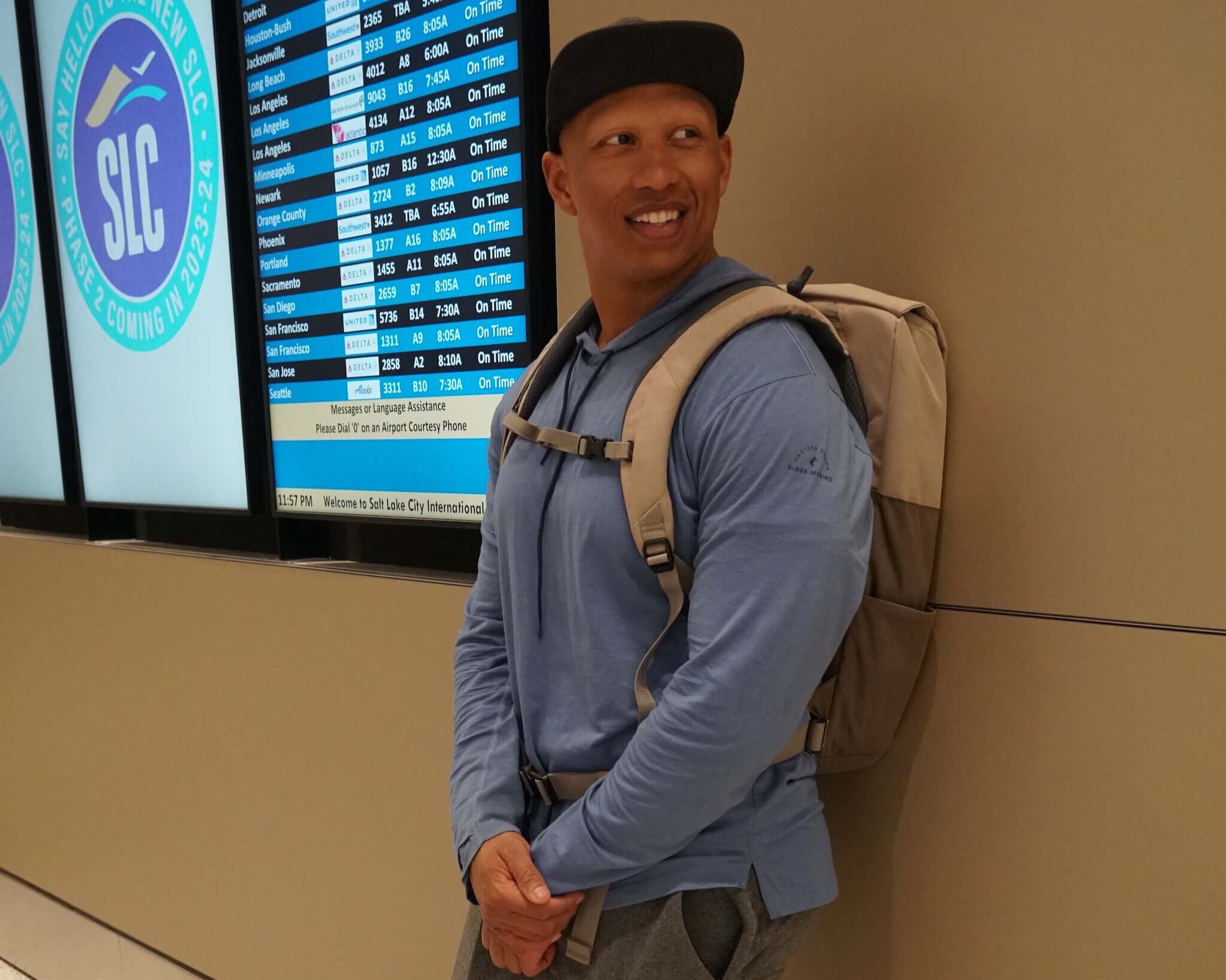 World traveler Khai Johannes knows exactly what to wear traveling - he's wearing the Solstice Hoodie in front of a flight departures board at an airport