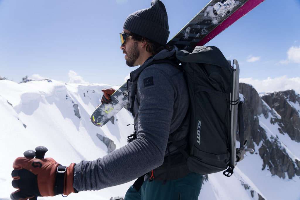 Sam Cohen carries his skis on a sunny backcountry ski tour
