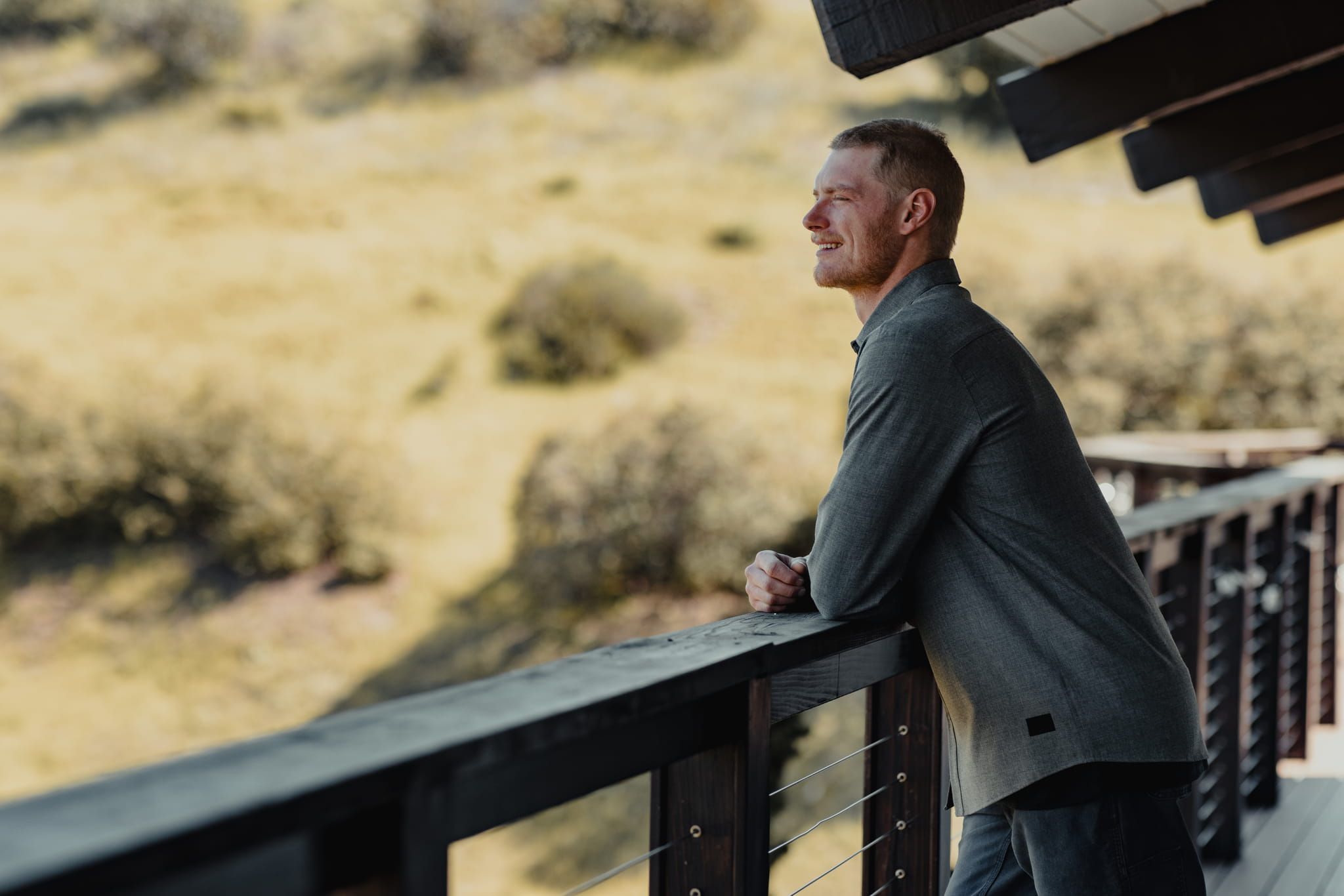 a man wearing the High Country Button Down leans on a railing looking out