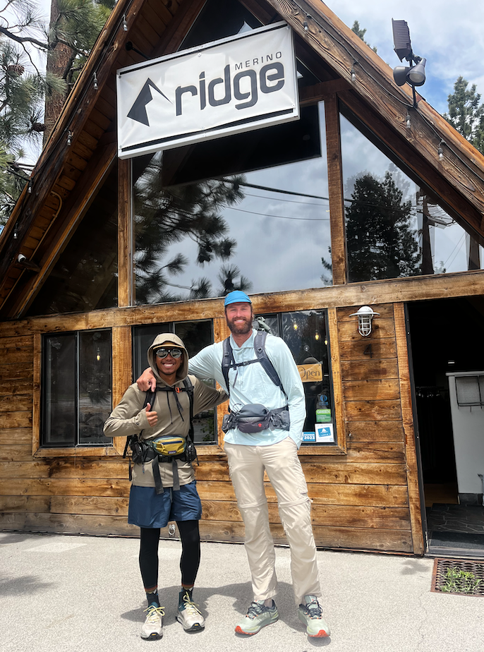 Two PCT hikers pose for a photo outside the Ridge Collective storefront in Mammoth Lakes wearing new Solstice Sun Hoodies