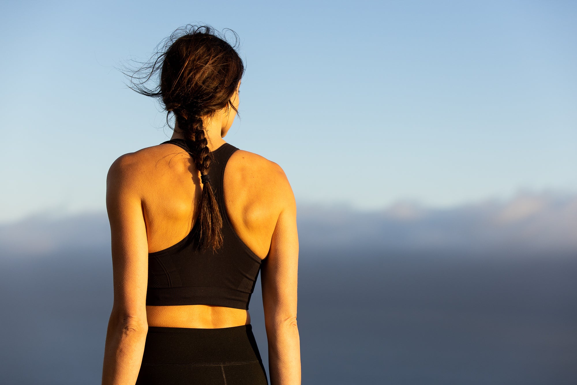 a woman on a trip wearing a Send-It Merino Wool Sports Bra looking out over cloudy mountains