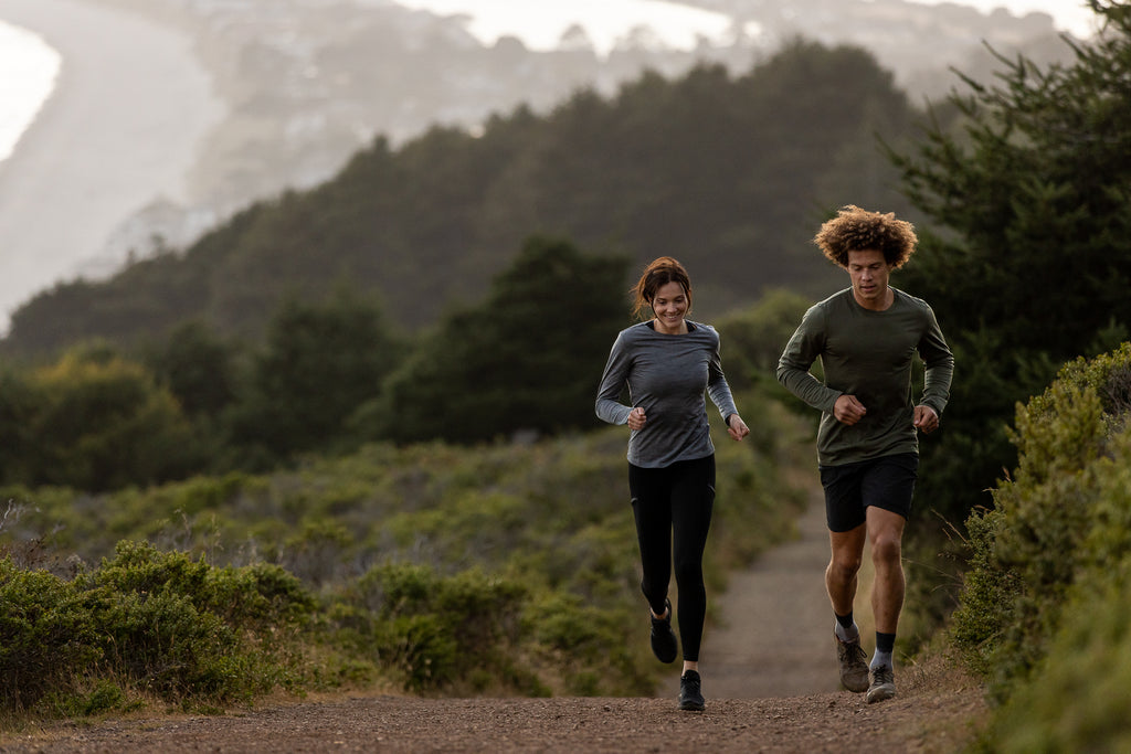 a man and a woman wearing Ridge Merino gear go for a trail run in the mountains