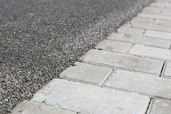 The boundary between the mulch rubber playground and the sidewalk tiles.