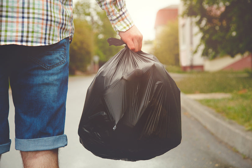 young man taking out garbage in black plastic bag