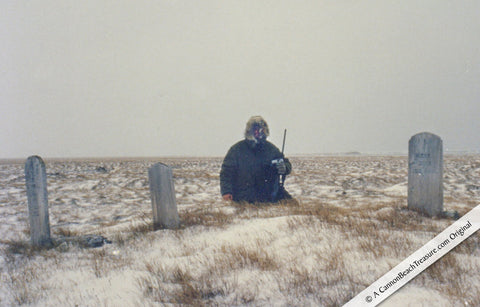 Robert Lewis Knecht ORCA Project 250 miles inside the Arctic Circle holding camera and rifle next to 19th century graves of whaling ship crew members