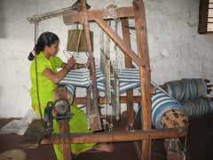 A rural Indian woman weaving cotton on a handloom.