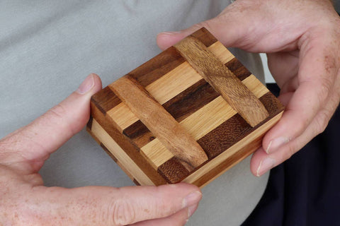 zweifarbige Geschenkebox aus Holz wird in den Händen gehalten.