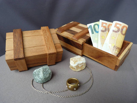 zwei Geschenkboxen aus Holz liegen nebeneinander und sind mit Geldscheinen gefüllt.