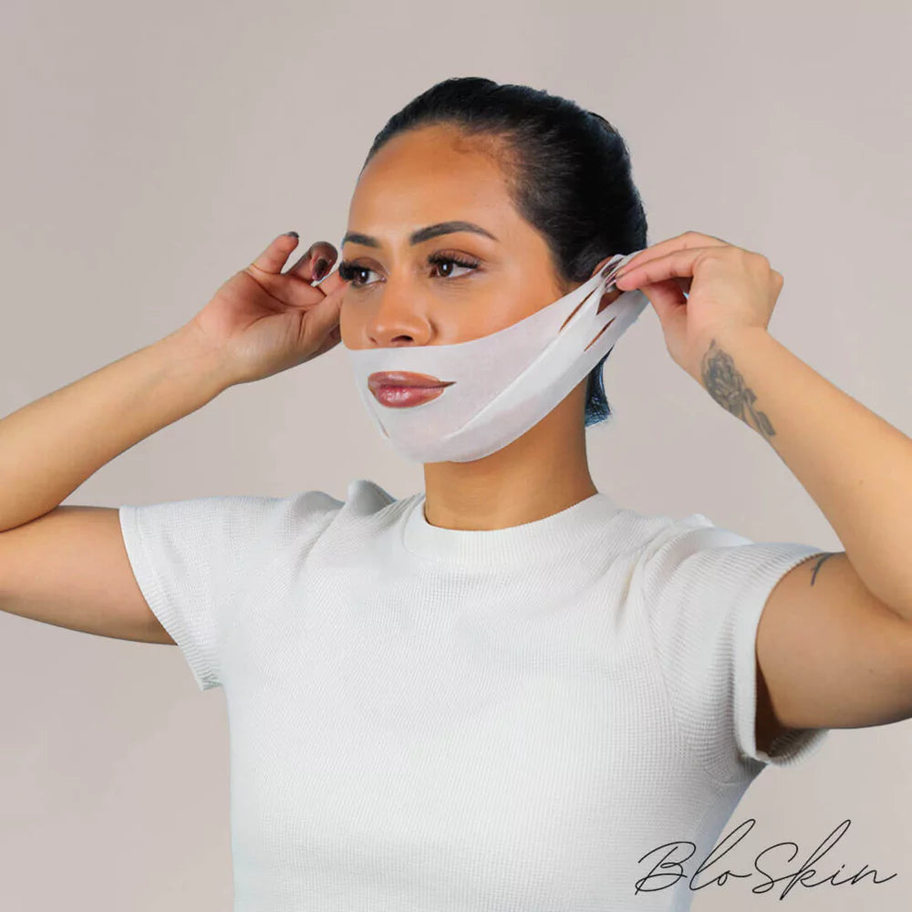 Woman adjusting a transparent face mask on a light background.