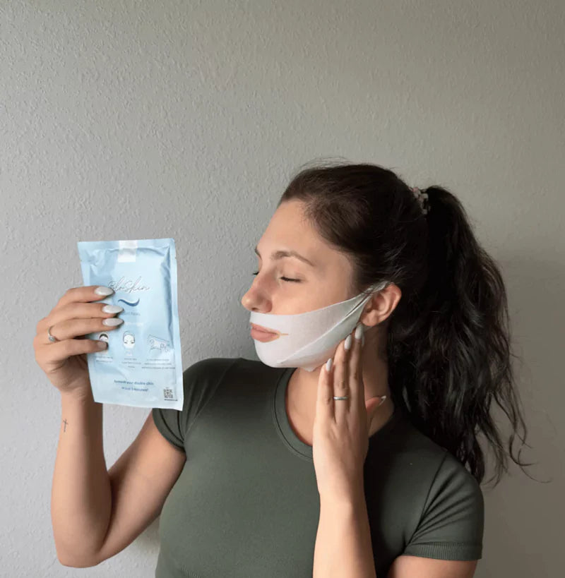 Woman with eyes closed holding a skin-care product while wearing a white facial mask.