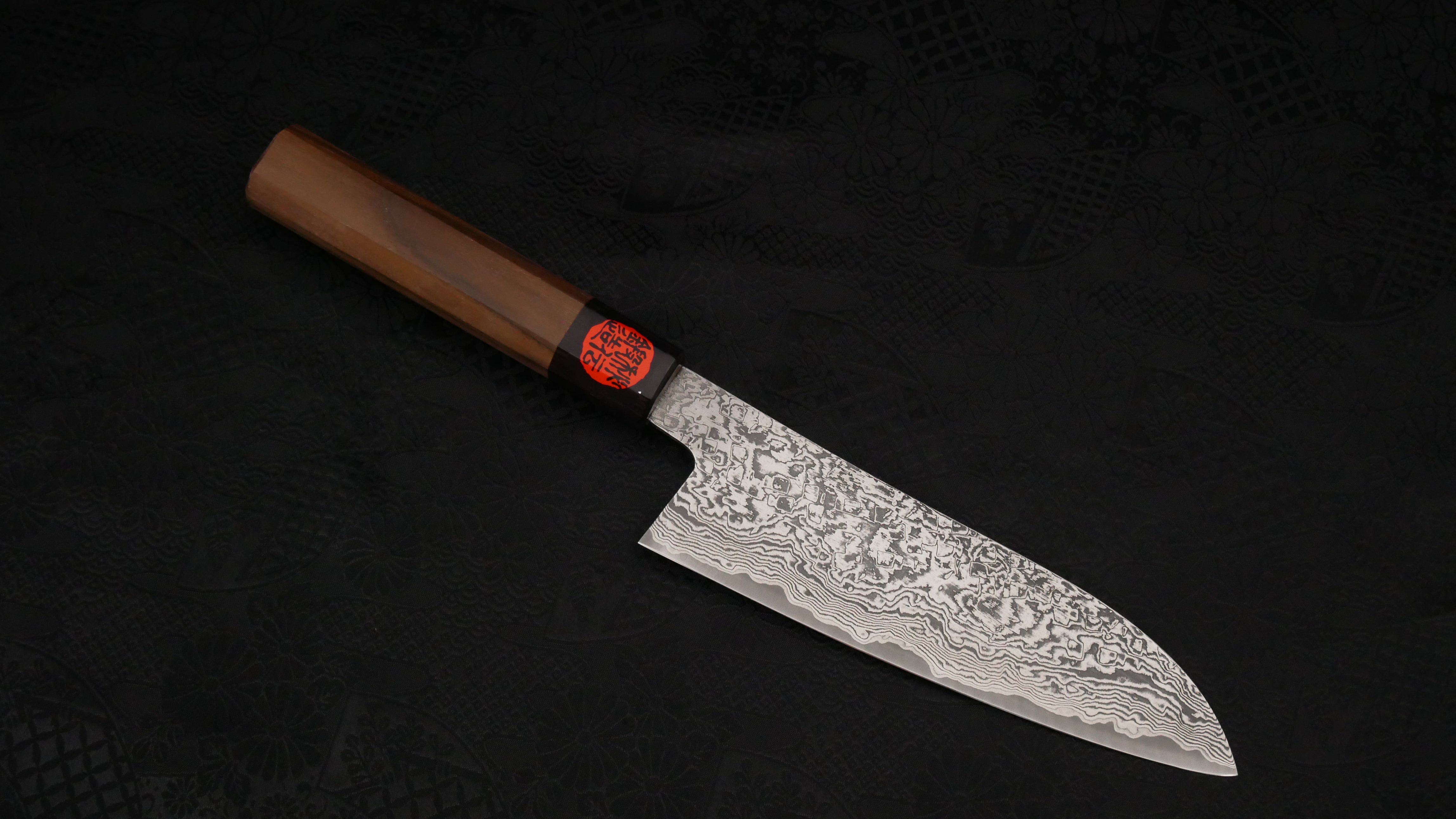 The Santoku knife against a dark background.