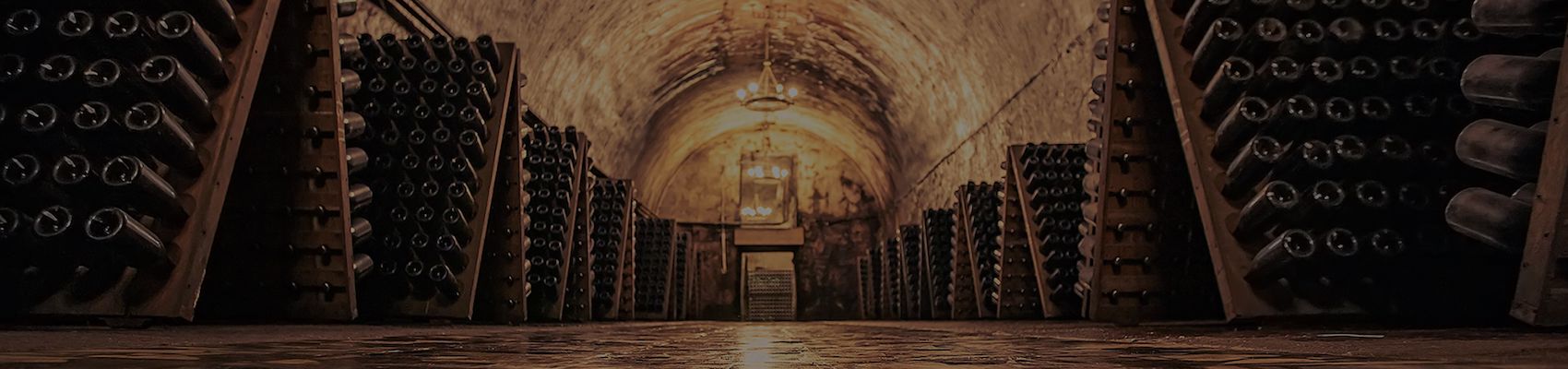 Alter Weinkeller mit Champagner Flaschen in Rüttelpulten und Kronleuchtern an der Decke