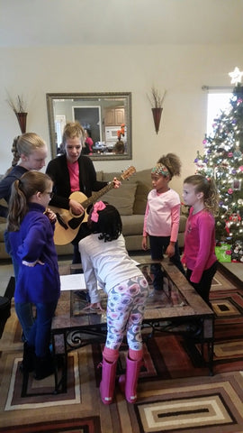 the girls rehearse songs with Sarah that they will be singing to the seniors for the day