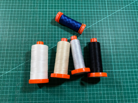 Aurifil Thread collection in white, cream, silver, black, and deep blue