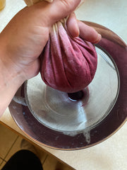 Elderberries being strained and squeezed through cheesecloth