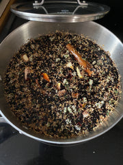 Elderberries and herbs in water in a saucepan