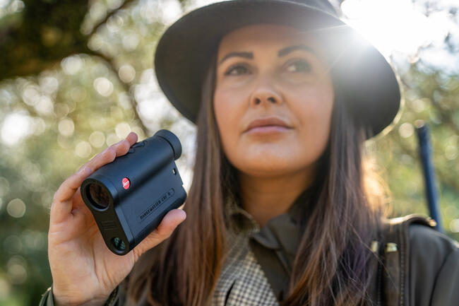 A huntress using a Leica Rangemaster CRF R for precise distance measurement