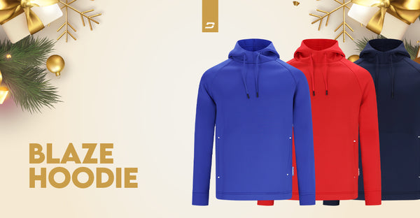 Three Blaze Hoodies in vibrant blue, red, and navy, presented against a holiday-themed backdrop with ornaments and lights.