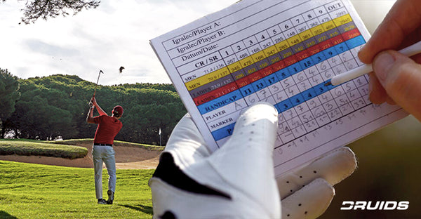 Detailed view of a golfer's hands marking scores on a colorful scorecard on a golf course.