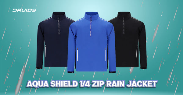 Three quarter-zip rain jackets from Druids in navy blue, royal blue, and black, featuring water-resistant material, prominent zippers, and the Druids logo on the chest, advertised as 'Aqua Shield' against a backdrop of stylized rain.